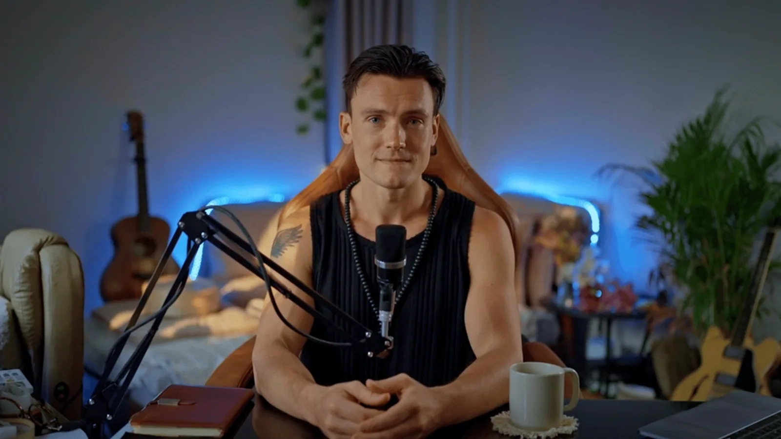 The coach at a desk with a microphone, a notebook and a cup of tea, ready to talk