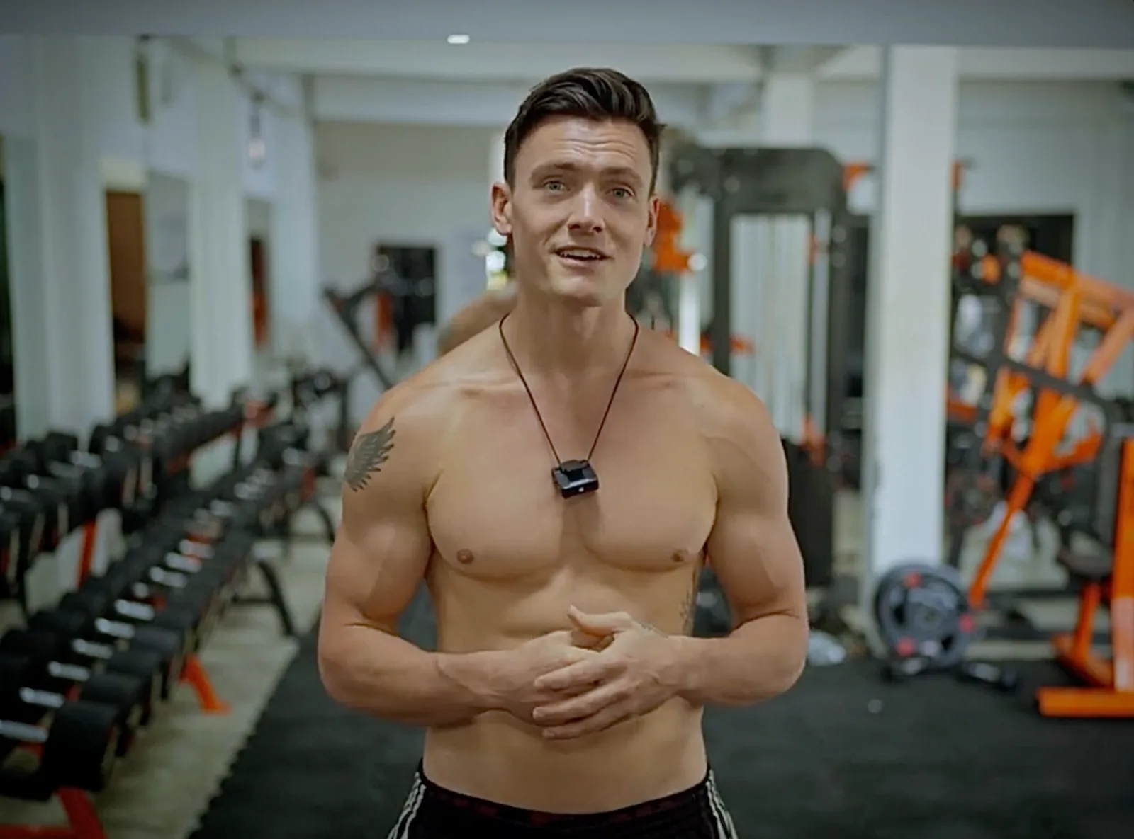 The coach in a gym between the racks, mid-sentence
